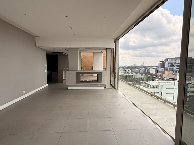 Spacious open-plan living area featuring large sliding glass doors, a built-in fireplace, and seamless access to a balcony with expansive city views.