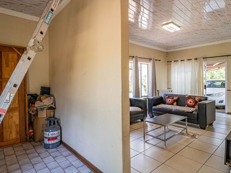 A living room area featuring tiled flooring and PVC ceiling panels, with direct access to an outdoor space through a sliding glass door.