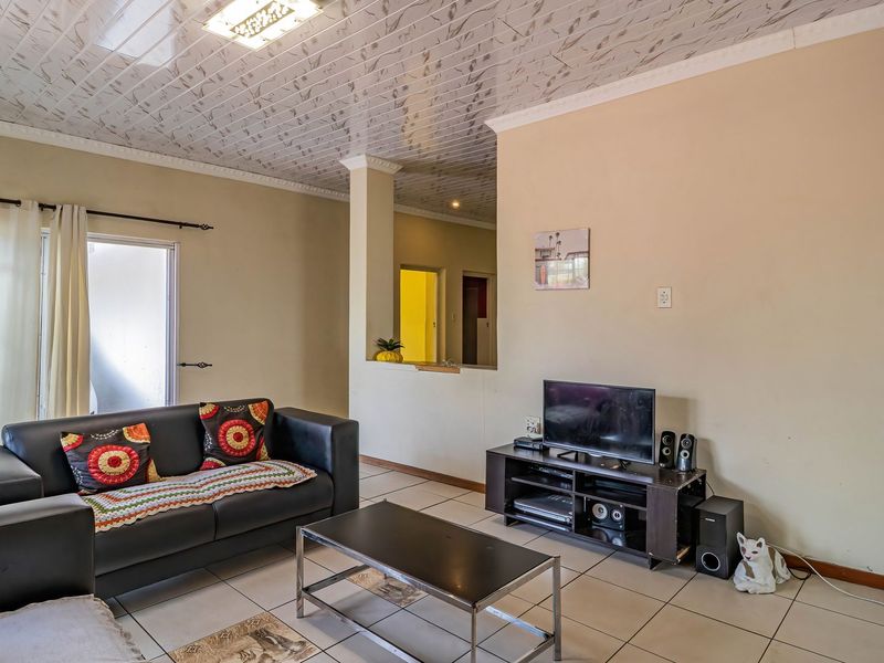 A living room featuring tiled flooring and decorative ceiling panels, with a sliding glass door providing access to the exterior.
