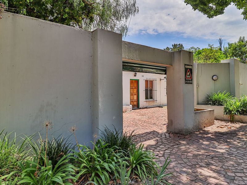 Front entrance area featuring a paved driveway, secure boundary wall, and gated access to the main residence.
