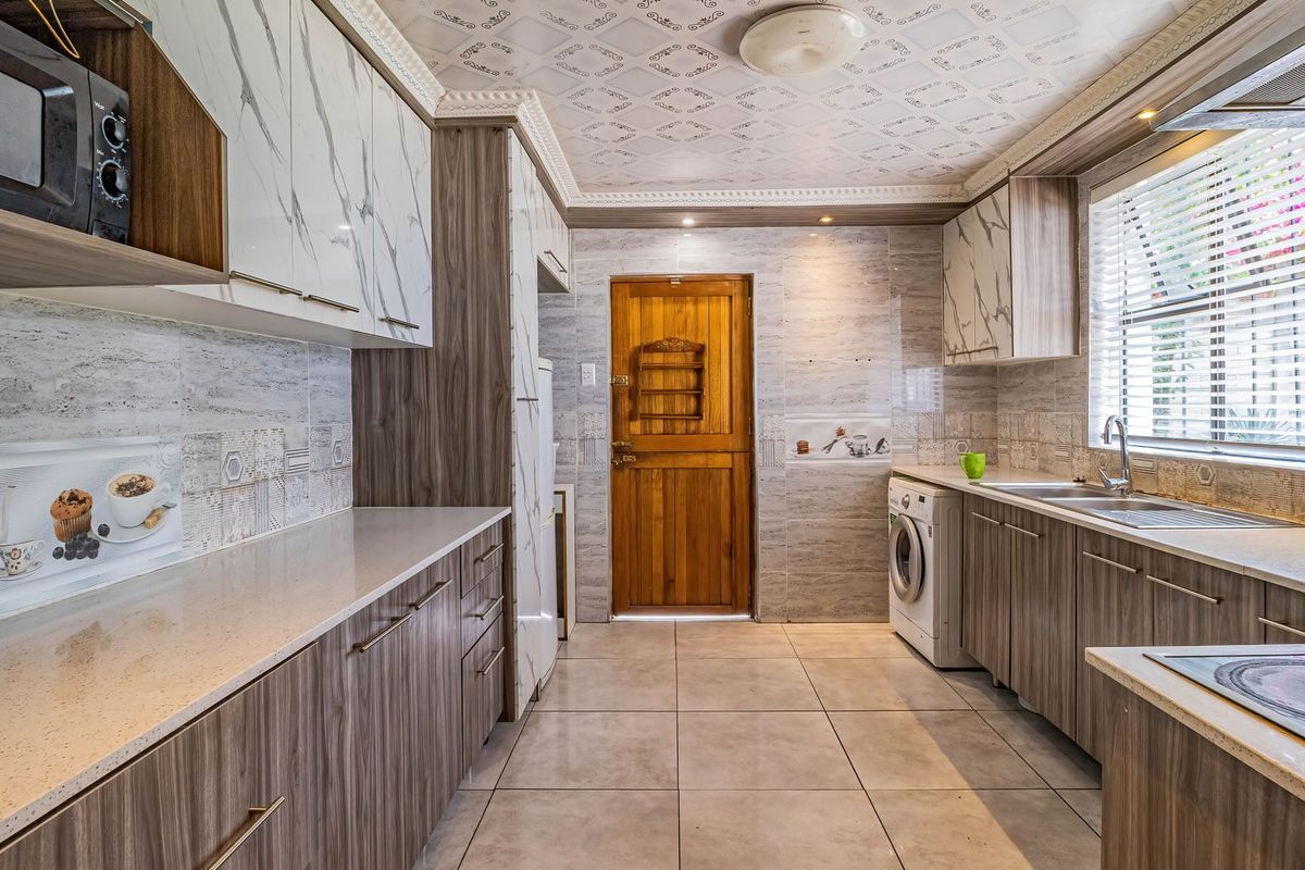 A well-appointed kitchen featuring modern wood-grain cabinetry, stone countertops, integrated appliances, and tiled finishes throughout.