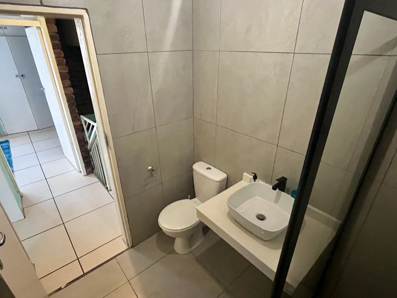 A modern bathroom featuring large-format wall tiles, a contemporary vessel basin on a floating vanity, and a glass-enclosed shower area.