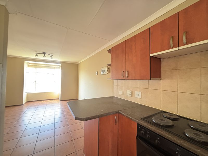Open plan kitchen and living area featuring tiled flooring, built-in cabinetry, and an electric hob, offering a functional layout with natural light.