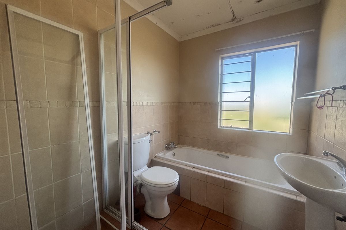 A dated bathroom featuring a shower enclosure, bathtub, and pedestal basin, requiring cosmetic updates and ceiling repairs.