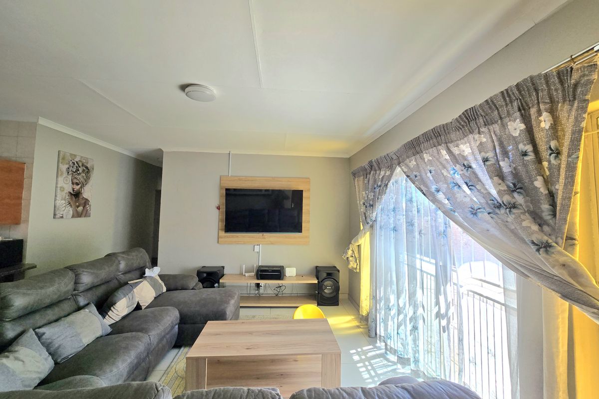 A comfortable living room featuring tiled flooring and a large sliding glass door that provides ample natural light.