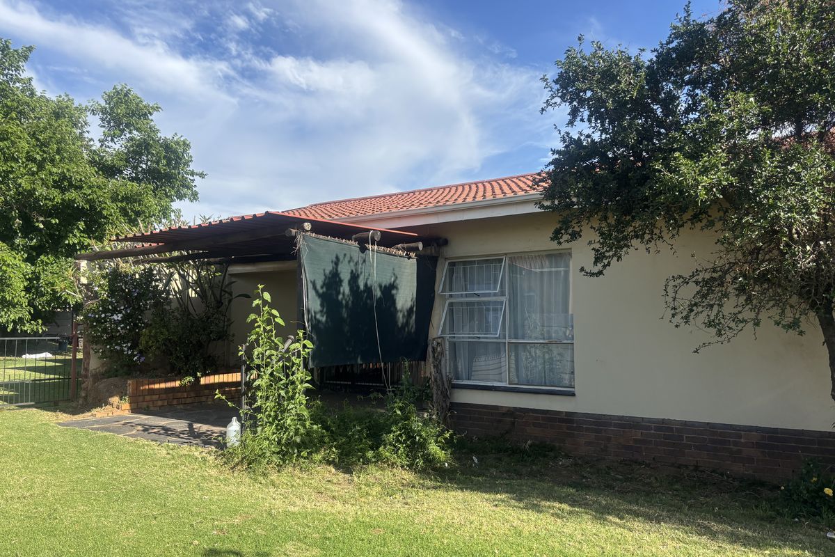 Rear view of the property featuring a covered patio area, tiled roof, and established garden space with lawn.