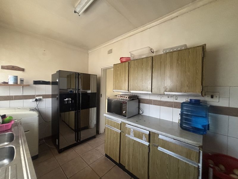 A functional kitchen featuring dated laminate cabinetry, tiled backsplash, and tiled flooring, offering significant potential for a modern renovation.