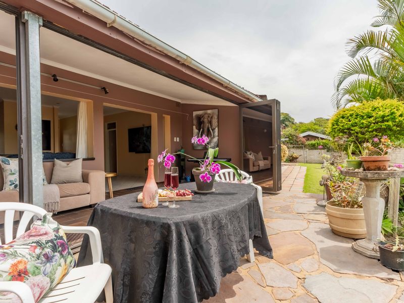 A covered patio area featuring stone paving and folding glass doors that provide seamless access to the interior living space.