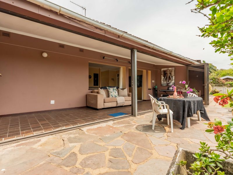 A covered patio area featuring tiled flooring and large sliding glass doors, leading out to a stone-paved outdoor space.