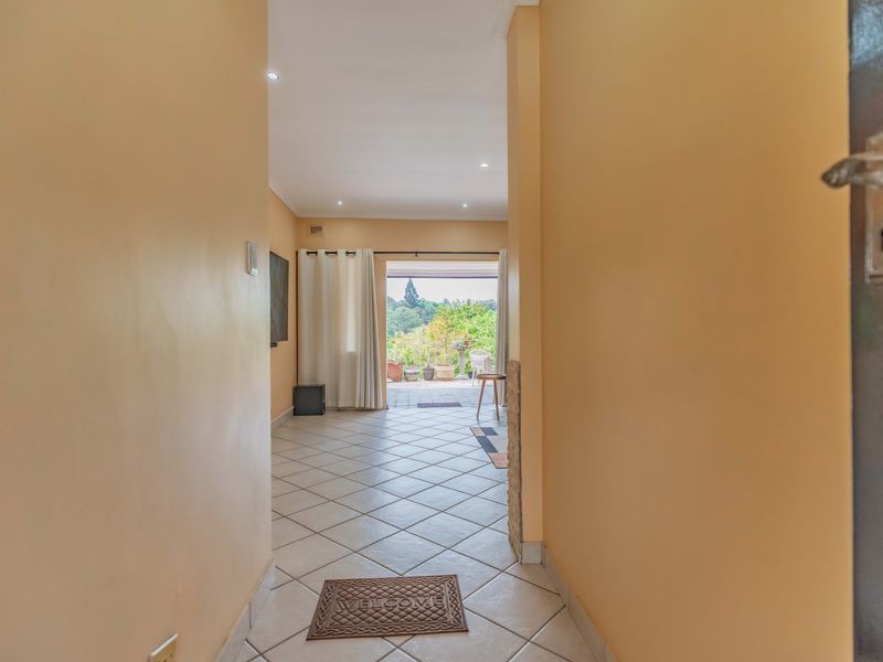 A bright entrance hallway featuring tiled flooring and a stone-clad feature wall, leading directly through to an outdoor patio area.