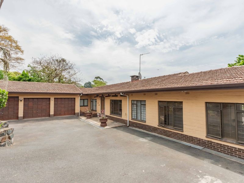 Front exterior view of a single-story house featuring a double garage, tiled roof, and paved driveway area.