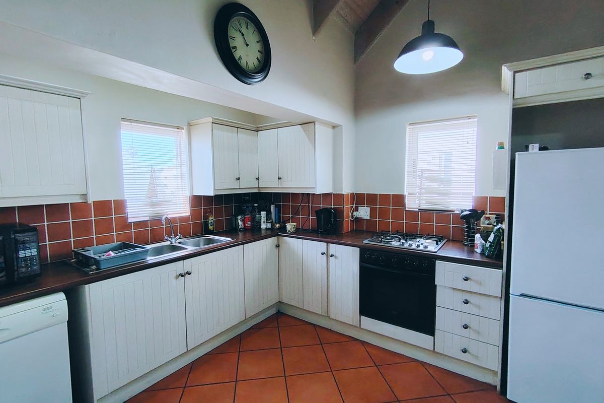 A functional kitchen featuring white cabinetry, a gas hob, built-in oven, tiled backsplash, and vaulted ceilings with pendant lighting.