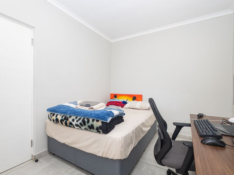 A compact bedroom featuring neutral wall finishes, tiled flooring, and cove cornicing, suitable for use as a guest room or home office.