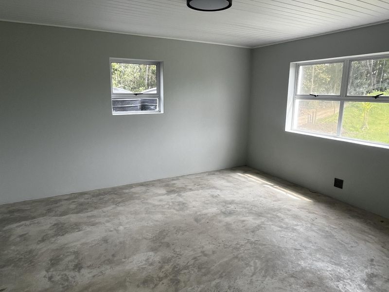 A bright, empty bedroom featuring a tongue and groove ceiling, flush mount lighting, and unfinished concrete flooring, ready for final floor finishes.