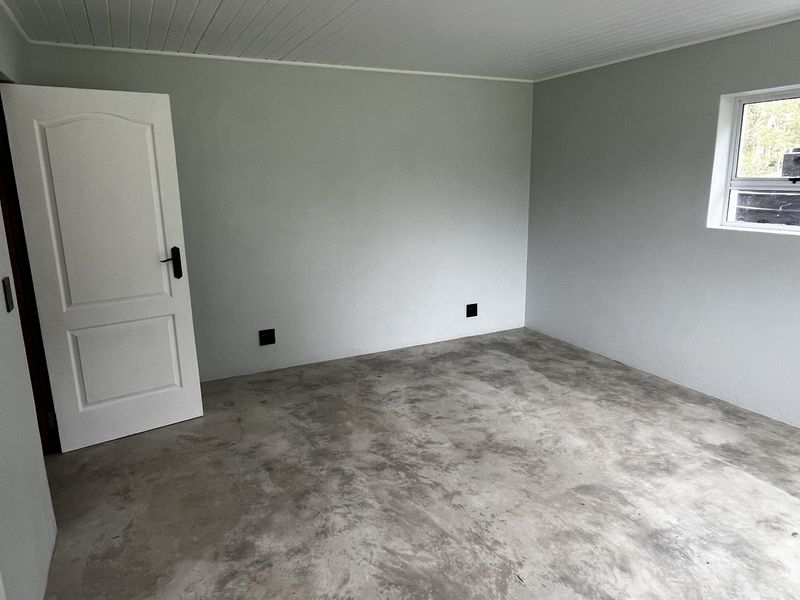 A clean, empty bedroom featuring polished concrete flooring, a white tongue and groove ceiling, and neutral wall finishes, ready for personalization.