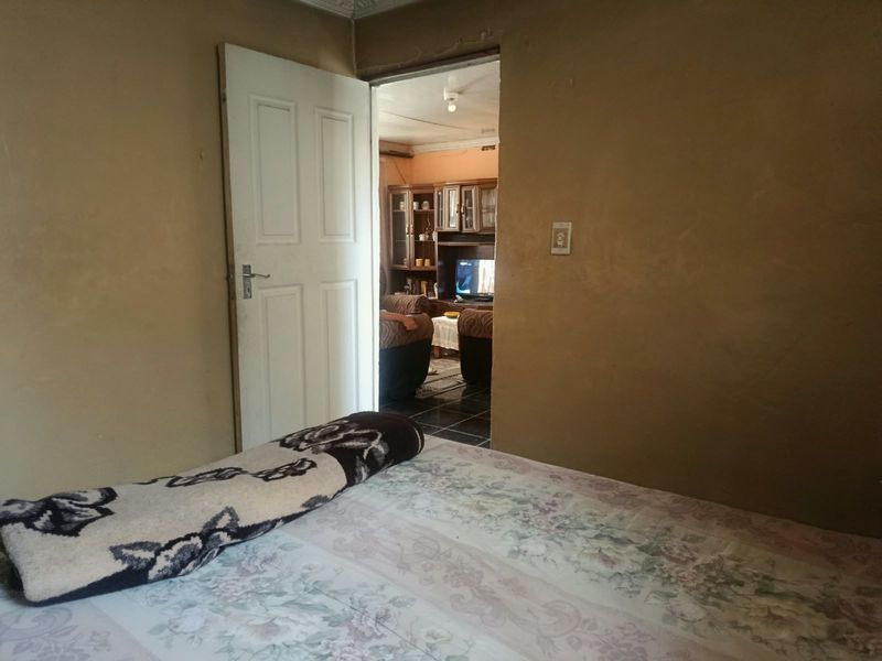 A bedroom interior featuring plain wall finishes and an internal door leading to an adjacent living space.