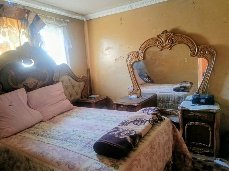 A bedroom featuring crown molding, currently requiring significant wall repairs and cosmetic updates to improve the overall condition of the space.
