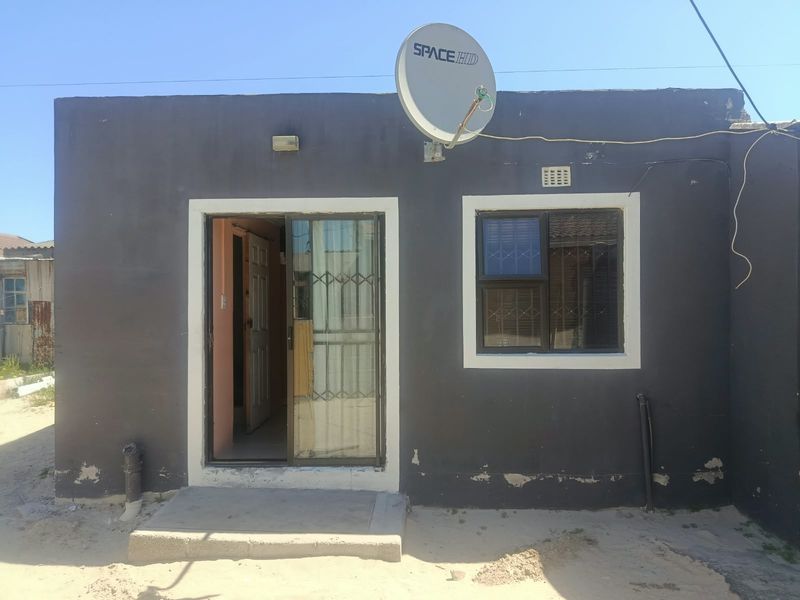 Rear exterior view of the property featuring a sliding door with security gate, window with burglar bars, and a satellite dish installation.