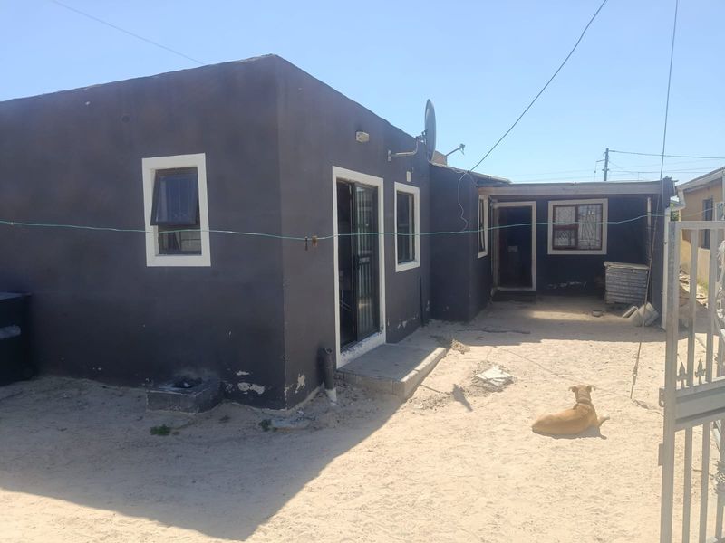 Rear view of the property featuring a dark-painted exterior, a covered patio area, and security features on windows and doors.