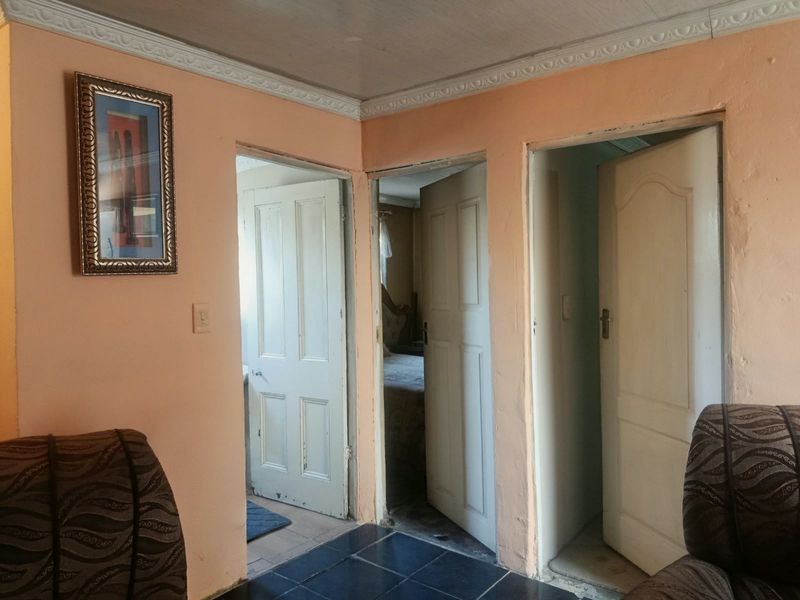 A hallway featuring tiled flooring, crown molding, and multiple panelled interior doors leading to adjacent rooms.