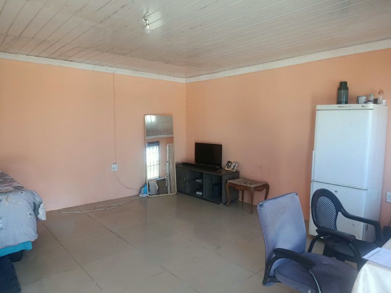 A living area featuring tiled flooring and a timber ceiling, offering a functional space with potential for cosmetic updates.