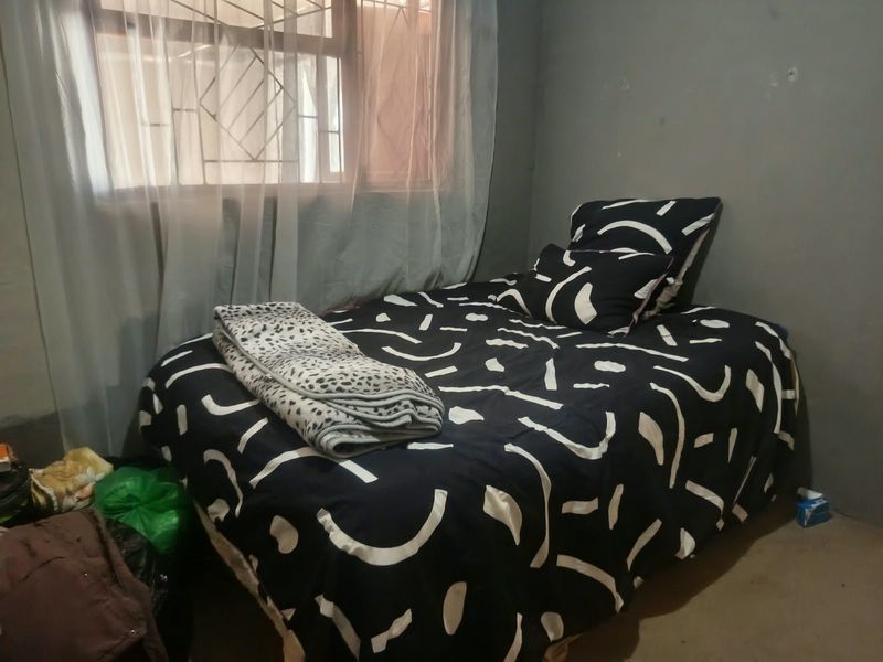 A bedroom featuring a window with security burglar bars and plain wall finishes.