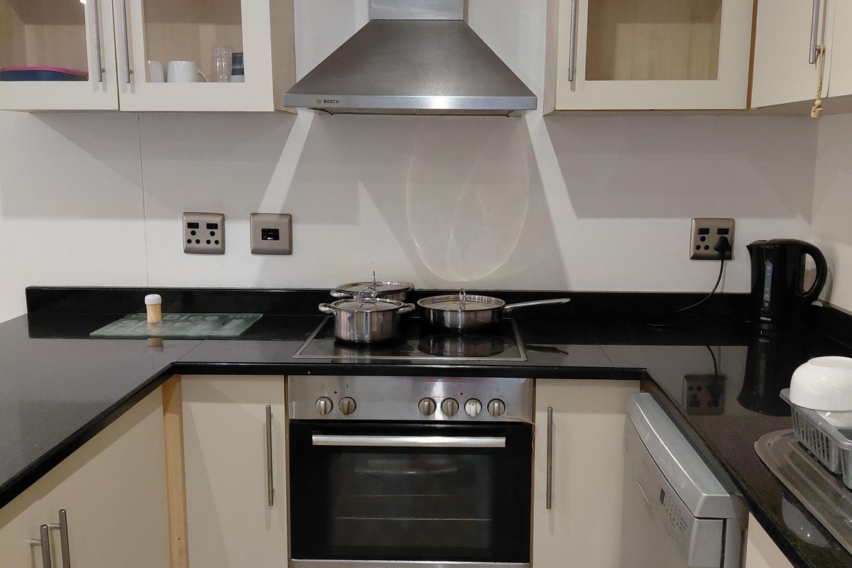 A functional kitchen featuring granite countertops, built-in cabinetry, a stainless steel oven, and an integrated dishwasher, providing a clean and practical cooking space.