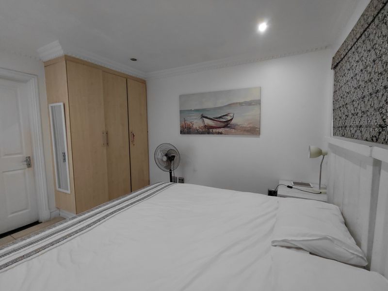 A well-maintained bedroom featuring built-in wooden wardrobes, recessed ceiling lighting, and decorative crown molding.