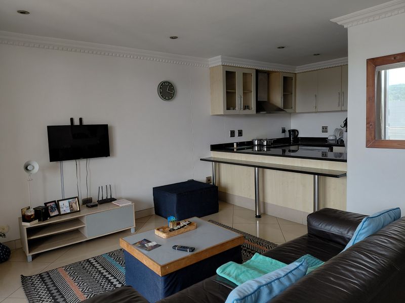 Open-plan living area featuring a functional kitchen with granite countertops, breakfast bar, and neutral cabinetry, seamlessly connected to the lounge space.