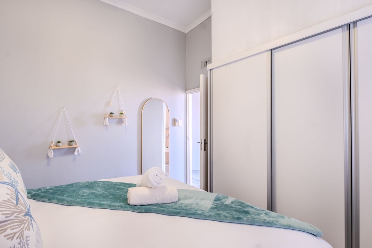 A well-maintained bedroom featuring a large built-in sliding door wardrobe and neutral wall finishes.