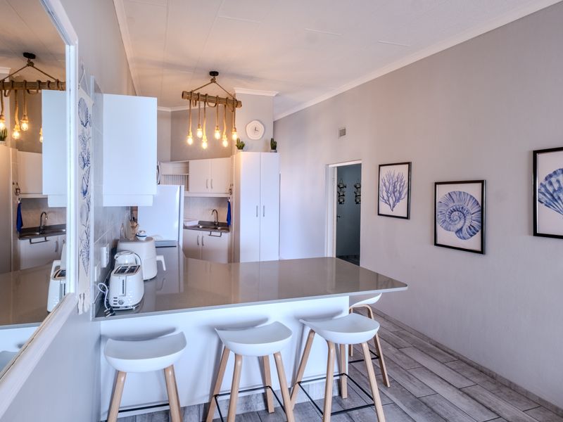 An open-plan kitchen and dining area featuring a breakfast bar, modern cabinetry, and tiled flooring, creating a functional and cohesive living space.