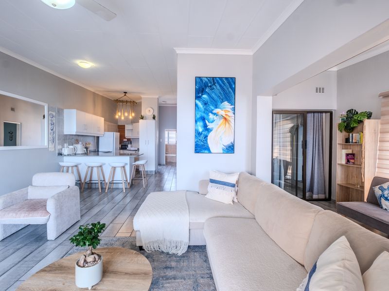 Spacious open-plan living area featuring a modern kitchen with island seating, tiled floors, and seamless flow to the adjacent living space.