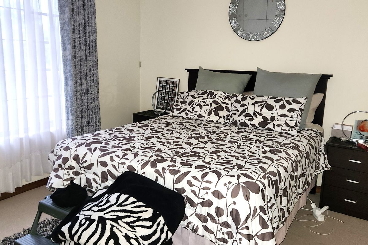 A functional bedroom featuring neutral wall tones, carpeted flooring, and a central ceiling fan, providing a comfortable and well-lit sleeping space.