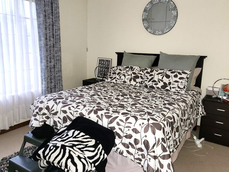 A functional bedroom featuring neutral wall tones, carpeted flooring, and a central ceiling fan, providing a comfortable and well-lit sleeping space.