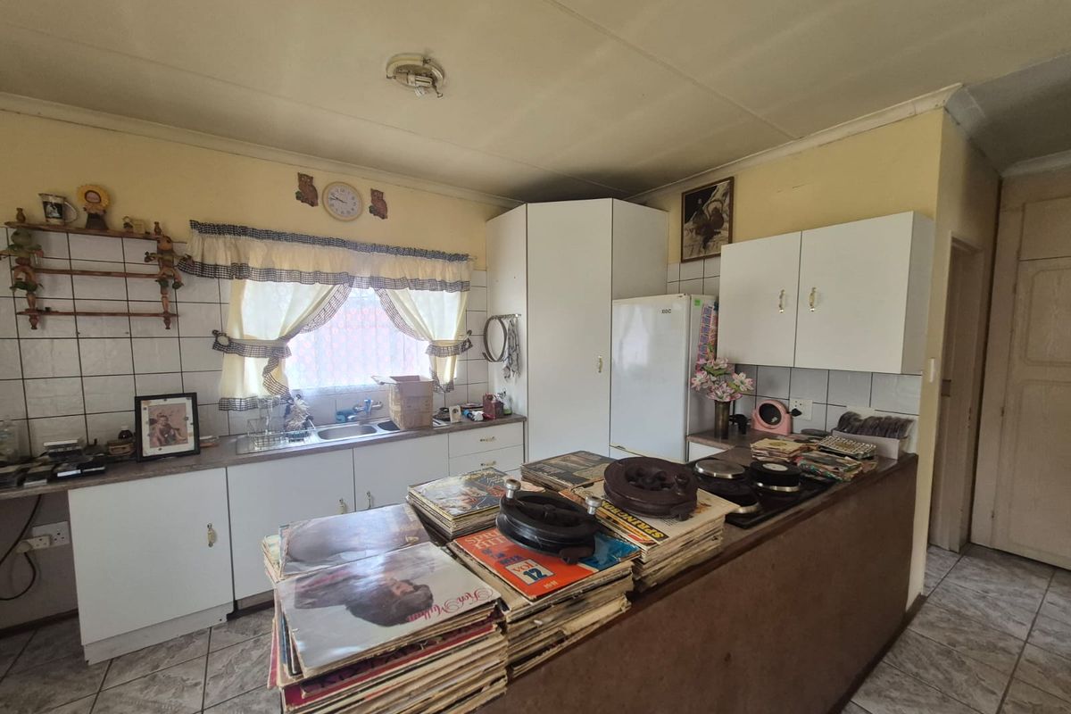 A dated kitchen featuring built-in cabinetry, tiled backsplash, and a central island with a built-in hob, offering potential for modernization.