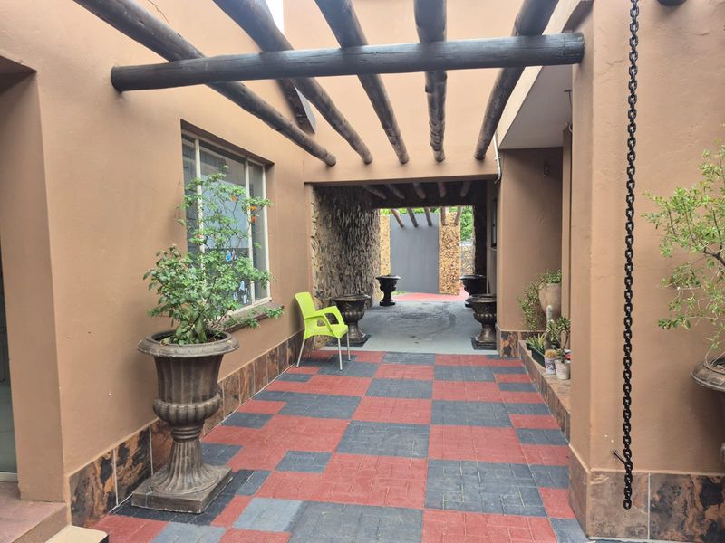 A covered patio area featuring a timber pergola, stone-clad feature wall, and patterned tiled flooring, providing a sheltered outdoor transition space.