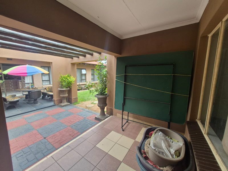 A covered outdoor patio area featuring tiled flooring and exposed timber beams, providing a functional space for outdoor relaxation and entertainment.