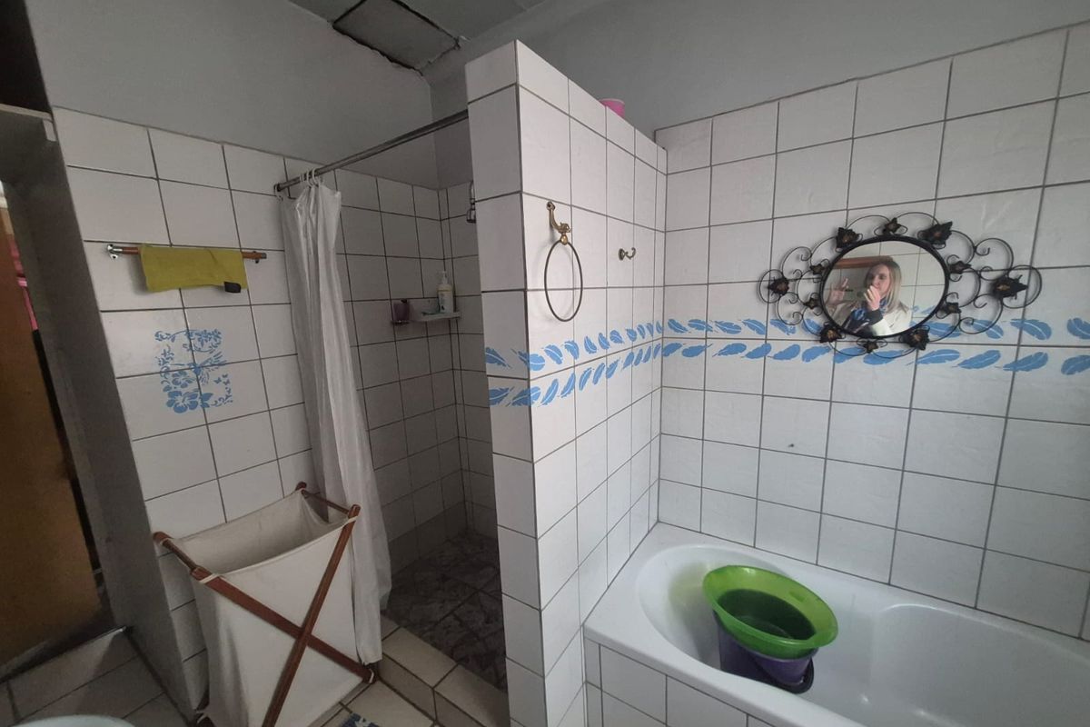 A functional bathroom featuring a built-in bathtub and a separate shower enclosure with tiled walls and flooring.