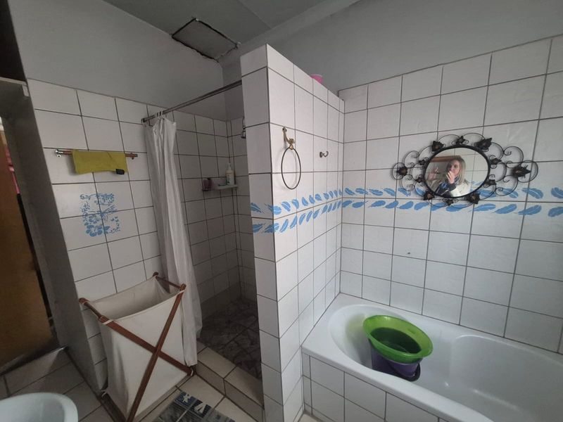 A functional bathroom featuring a built-in bathtub and a separate shower enclosure with tiled walls and flooring.