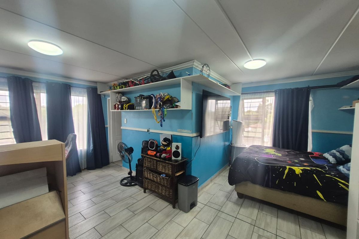 A bedroom featuring tiled flooring, built-in shelving units, and ceiling-mounted lighting, offering a functional space with potential for modern updates.