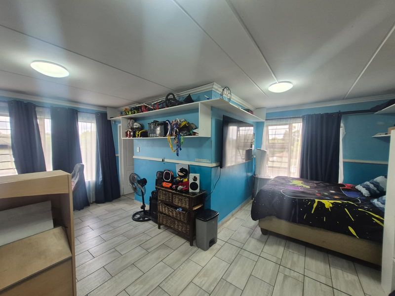 A bedroom featuring tiled flooring, built-in shelving units, and ceiling-mounted lighting, offering a functional space with potential for modern updates.