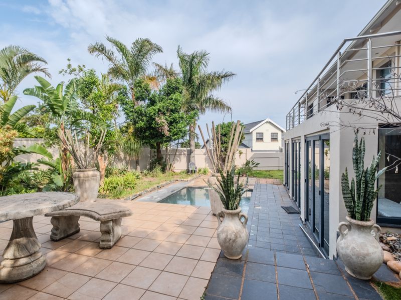 A well-maintained outdoor pool area featuring a tiled patio, swimming pool, and direct access to the home via sliding glass doors.