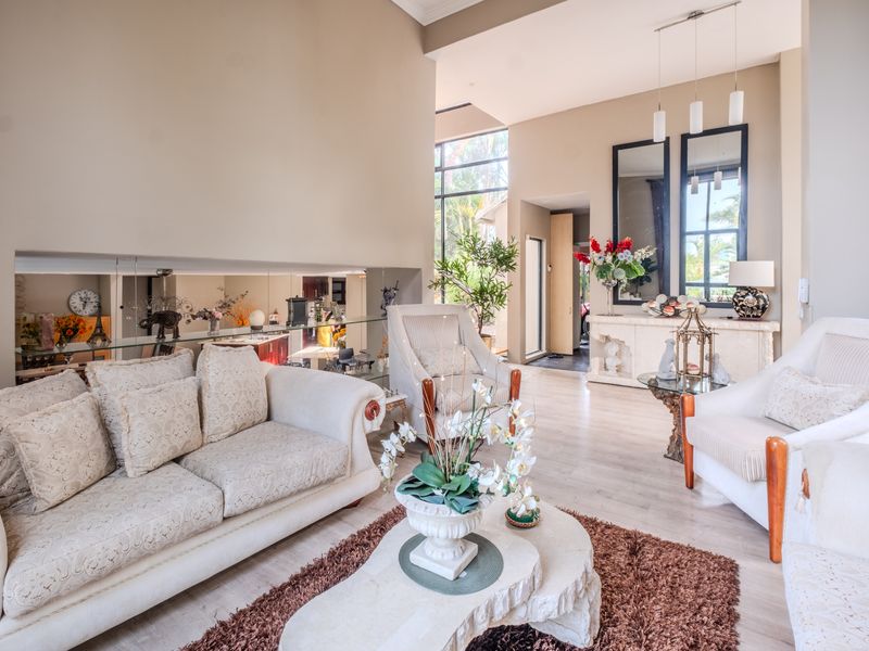 Spacious living room featuring high ceilings, large windows for natural light, and a decorative mirrored wall panel, creating an open and airy atmosphere.