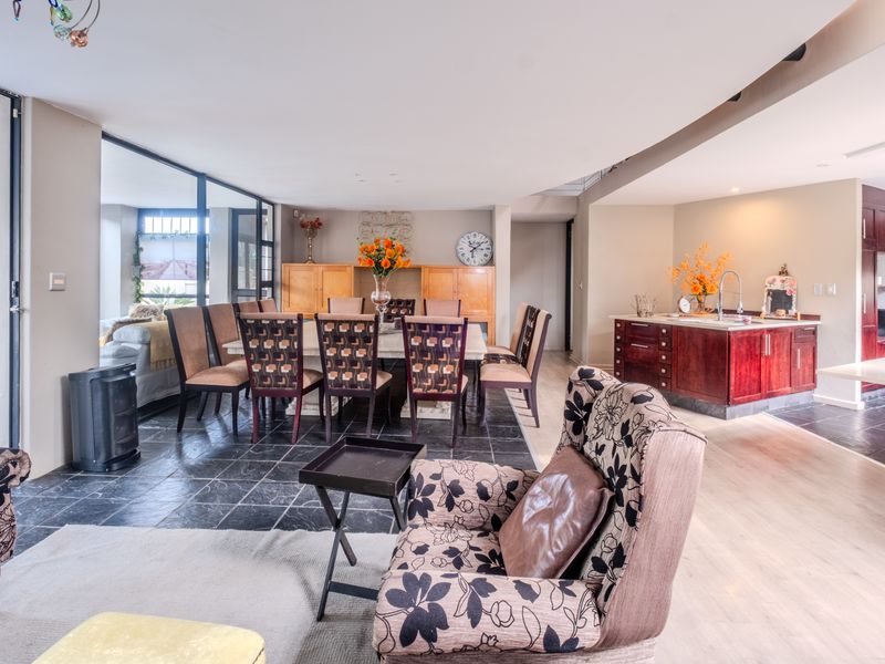 Spacious open-plan living and dining area featuring a mix of slate and laminate flooring, integrated kitchen cabinetry, and large sliding doors leading to the patio.