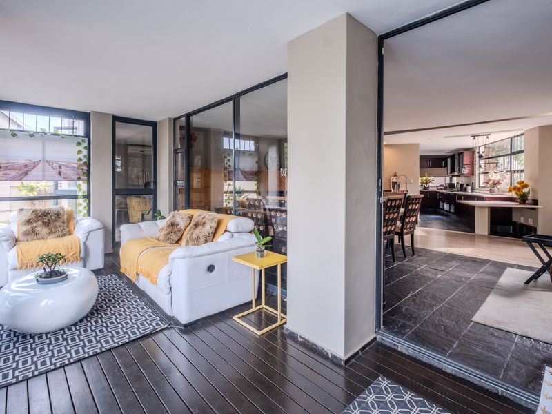 A spacious covered patio featuring timber decking and large glass sliding doors that provide a seamless transition to the interior living and kitchen areas.