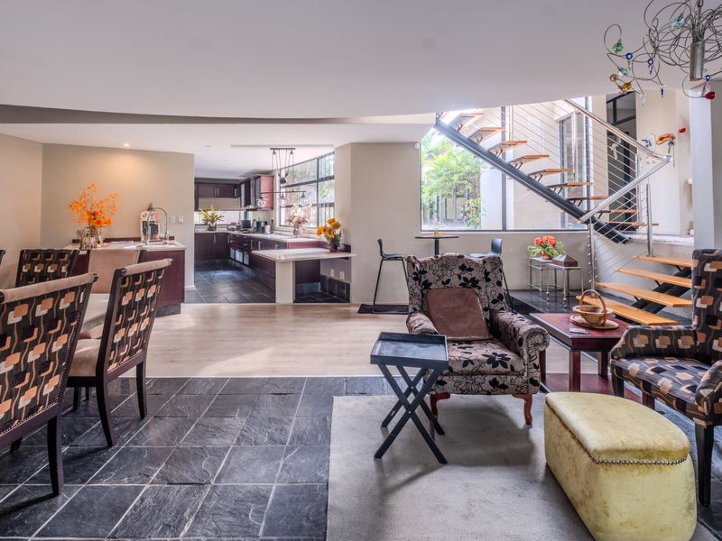 Spacious open-plan living and kitchen area featuring a mix of slate and laminate flooring, a modern floating staircase, and contemporary kitchen cabinetry.