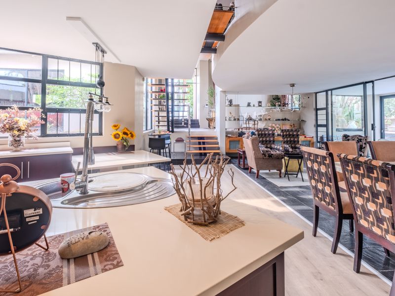 Spacious open-plan living and kitchen area featuring a central island, modern staircase, and large windows that provide ample natural light.