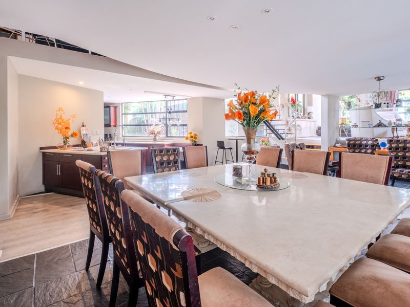 Spacious open-plan living and dining area featuring stone tile flooring, recessed lighting, and an integrated kitchen with built-in cabinetry.