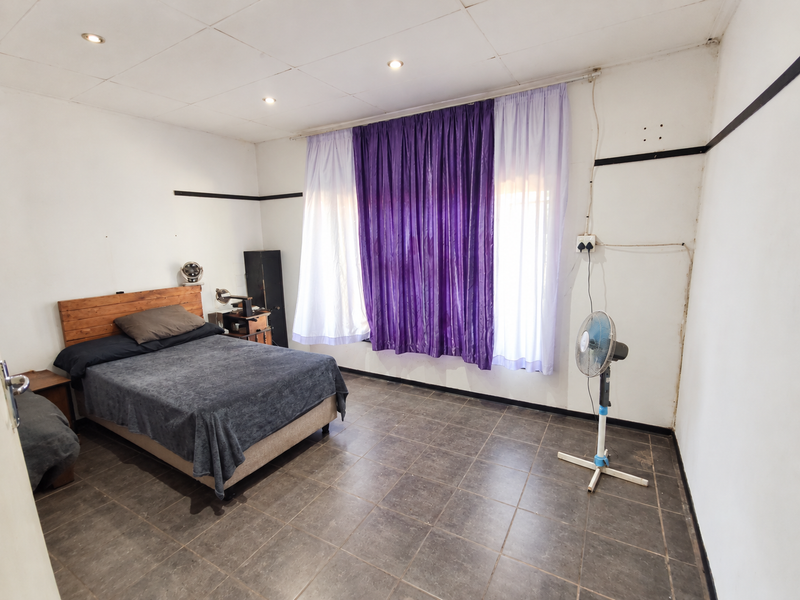 A bedroom featuring tiled flooring and recessed ceiling lighting, requiring minor cosmetic updates to the walls and electrical fixtures.