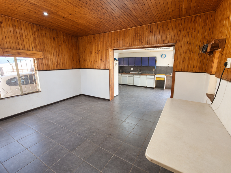 Open plan living and kitchen area featuring timber wall and ceiling paneling, tiled floors, and functional built-in cabinetry.